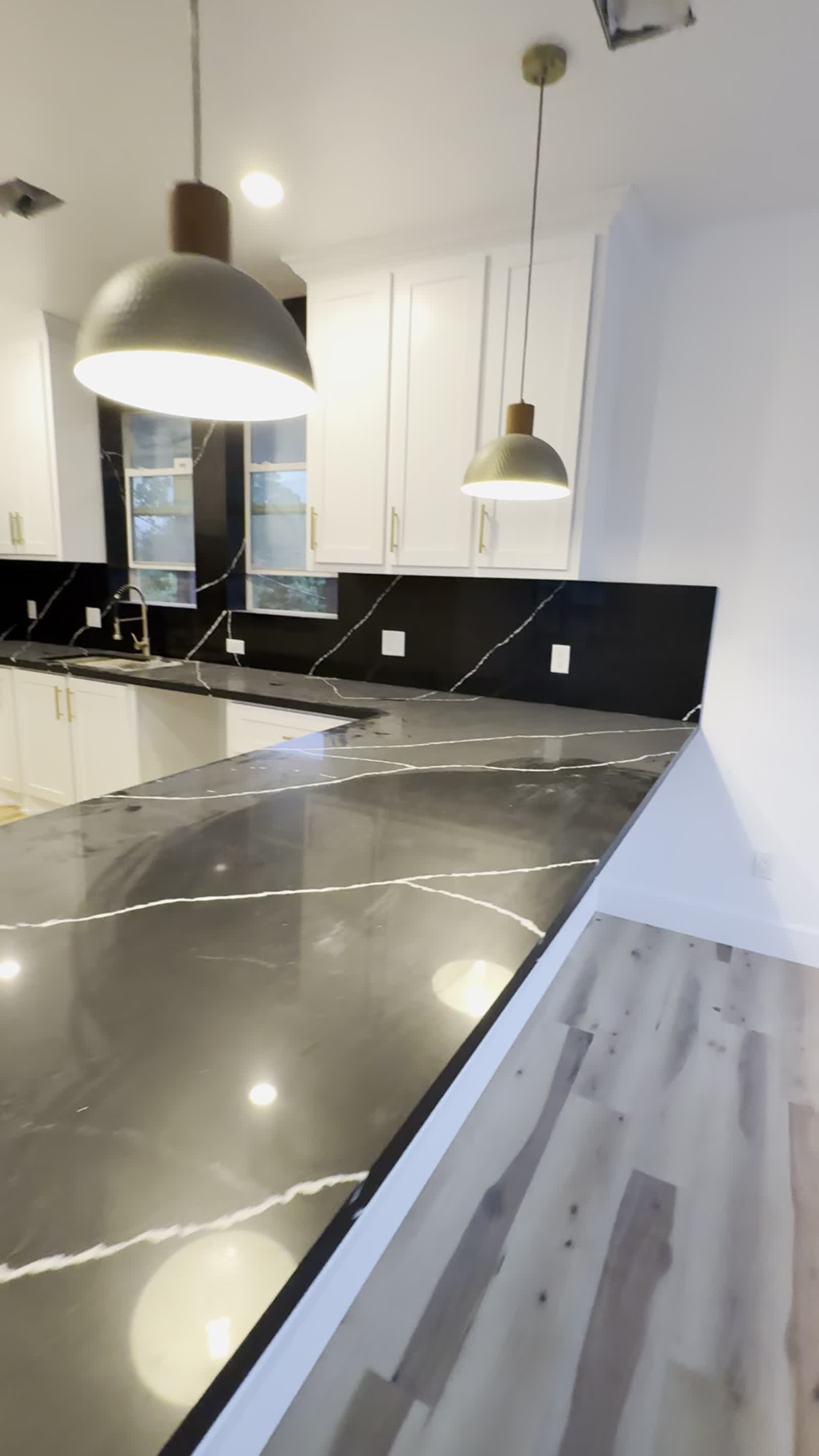 Black marble kitchen counter with white cabinetry and brass hardware