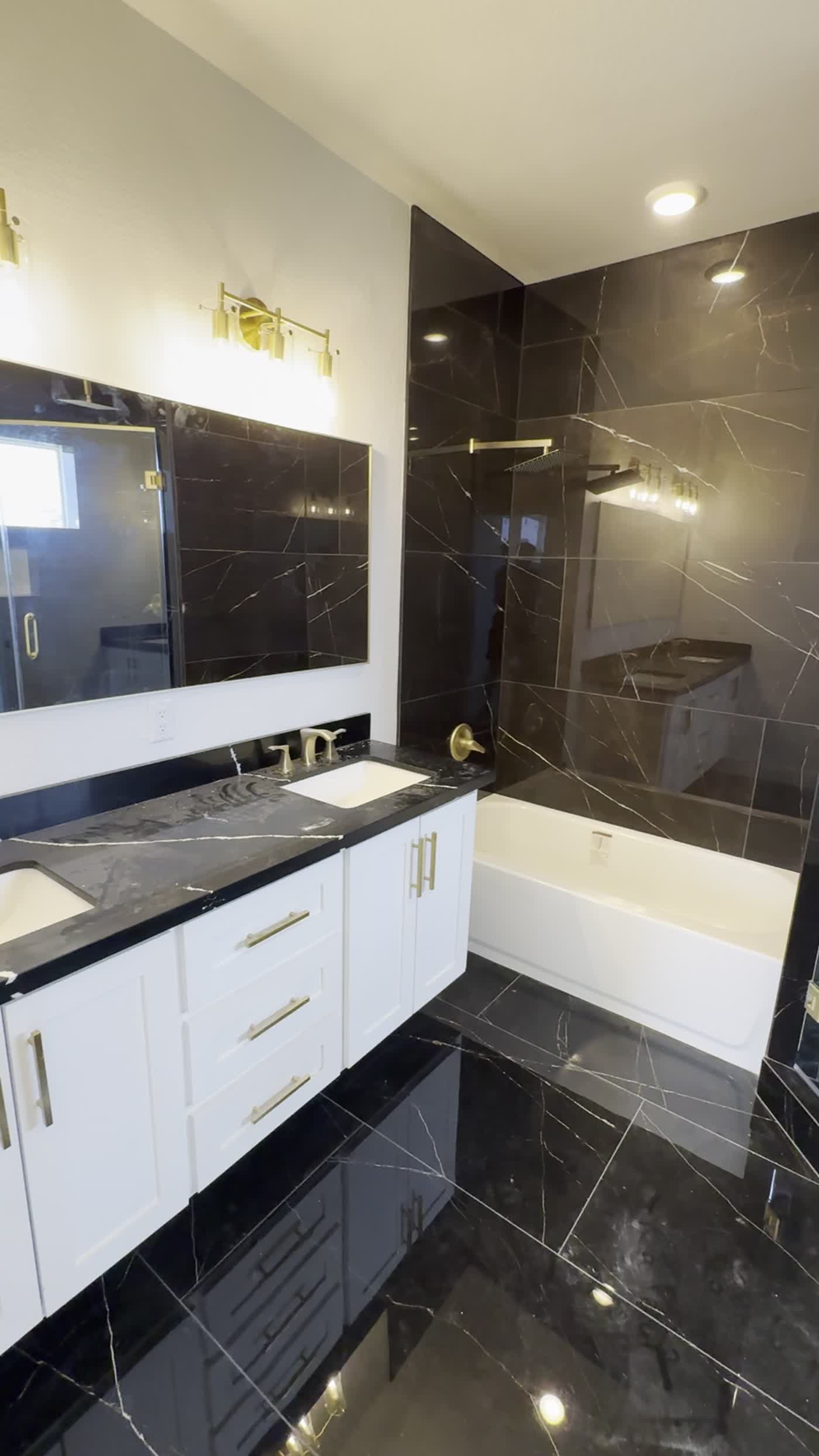 Bathroom remodel with glossy black tile and glass shower enclosure