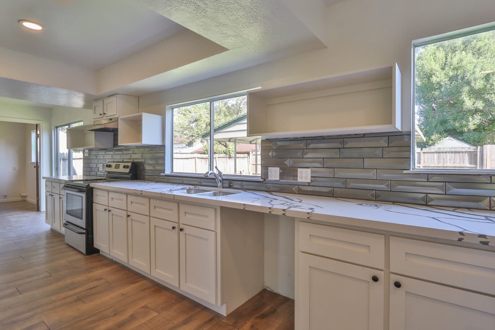 Open kitchen remodel with white cabinets and tile backsplash
